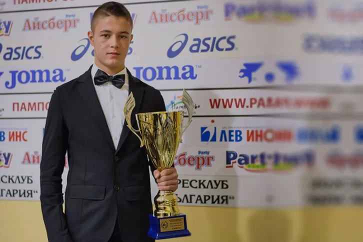 Young driver holding a first-place trophy from a rally event