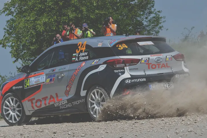Rally Hyundai taking a corner with a drift at a rally event