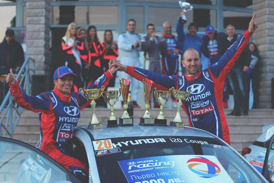 Vasil Jekov celebrating with his race trophies on the bonnet of his rally car